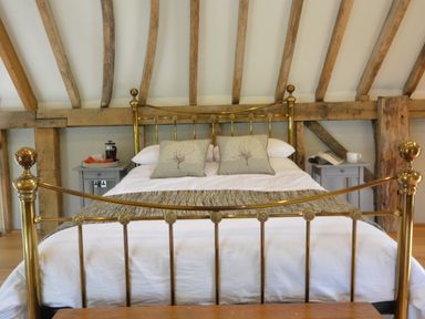 A bedroom with a brass bed frame two bedside tables with a coffee press and a book at Manor House Barn Peasenhall
