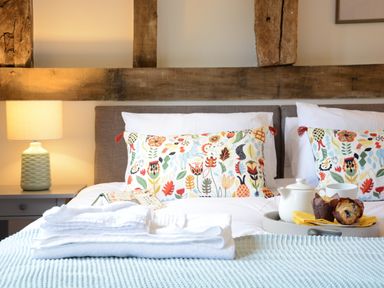 A bedroom with a double bed white towels on the bed a tray with teapot and muffins on the bed at Manor House Barn Peasenhall