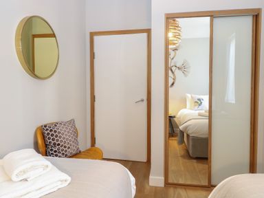 A bedroom with a bed and mirror at The Hive, Southwold
