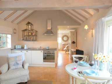 A kitchen and dining area with a round table set for two and an armchair at The Nookery at Snape Hall in Snape Suffolk