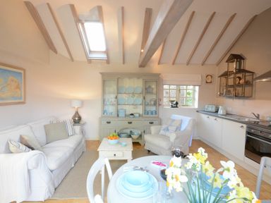 A kitchen and sitting area with a sofa armchair dining table and kitchen cabinets at The Nookery at Snape Hall in Snape Suffolk