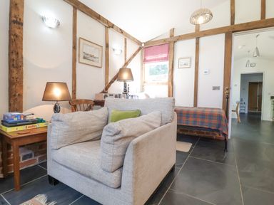 A living area with a cushioned armchair and table with board games at Yew Tree Farm Stable Worlingworth near Framlingham