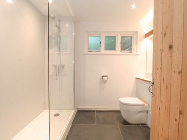A bathroom with a walk in shower toilet and three small windows at Yew Tree Farm Stable Worlingworth near Framlingham