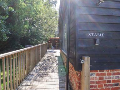 A stable with a wooden walkway leading to it at Yew Tree Farm Barn and Stable in Framlingham