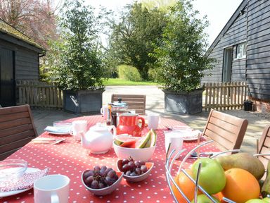 An outdoor dining table set with fruit and drinks at Yew Tree Farm Barn and Stable Framlingham