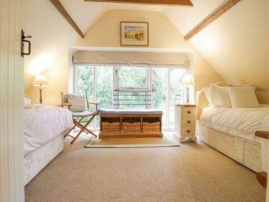 A bedroom with two single beds a wooden chair a storage bench and a window at The Cart House Sudbourne Near Orford