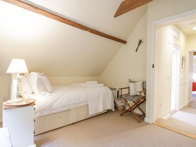 A bedroom with a single bed a bedside table with a lamp and a folding chair at The Cart House Sudbourne Near Orford