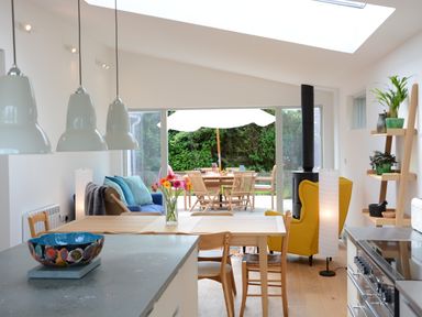A kitchen and dining area with wooden chairs table and a yellow armchair at 2 Pink Cottages in Aldeburgh