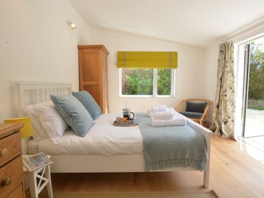 A bedroom with a bed holding towels and breakfast tray near a window with a yellow blind at 2 Pink Cottages Aldeburgh