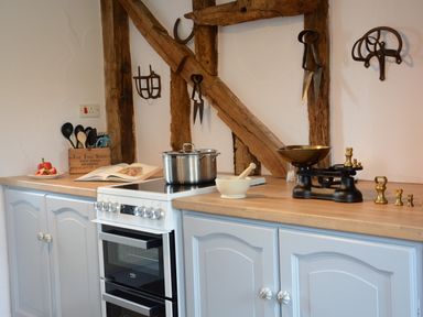 A kitchen countertop with a stove pot utensils book mortar and pestle and weighing scale at Wassicks Cottage Haughley