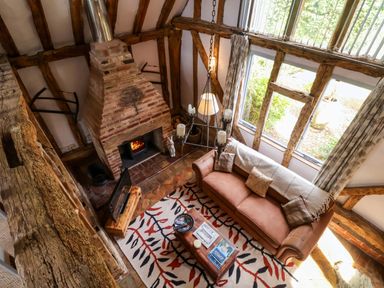 A living room with a fireplace and a sofa at Wassicks Cottage, Haughley