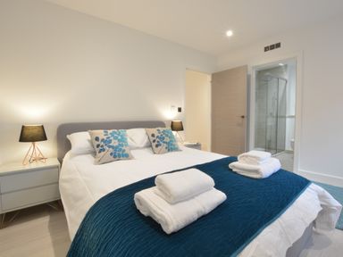 A bedroom with a double bed bedside tables lamps and an ensuite bathroom at Skylight Aldeburgh in Aldeburgh