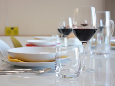A dining table set with white plates yellow napkins spoons a glass of red wine and an empty glass at Skylight Aldeburgh in Aldeburgh