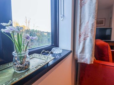 A living room with a window and decorative flowers at Pine Cottage in Woodbridge