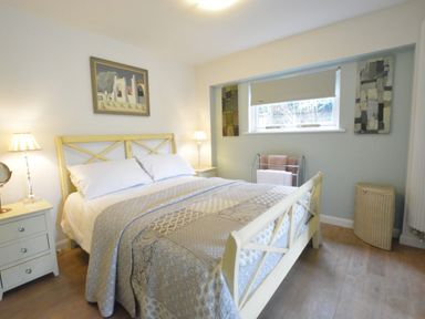 A bedroom with a double bed bedside tables lamps and a window with a blind at Robert Sadler's Studio in Aldeburgh