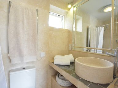 A bathroom with a towel on a rack above a toilet and a round sink on a tiled counter at Robert Sadler's Studio in Aldeburgh