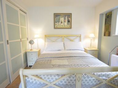 A bedroom with a double bed between two bedside tables with lamps and a wardrobe with sliding doors at Robert Sadler's Studio in Aldeburgh