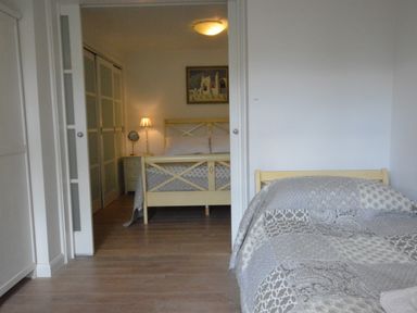A bedroom with two beds separated by sliding doors a bedside table lamp and a painting on the wall at Robert Sadler's Studio in Aldeburgh