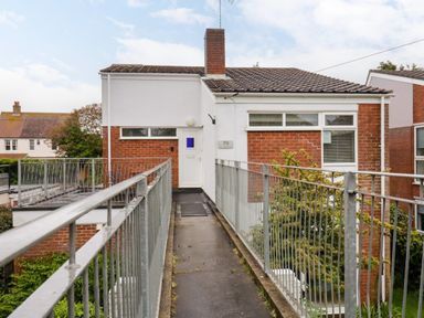 A walkway with railings leading to an entrance door on a two-story brick and white house at The Bridge House Southwold