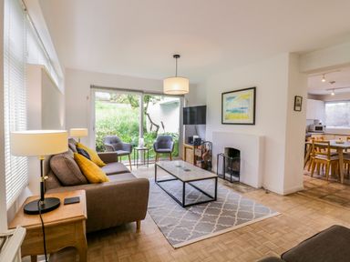 A living room with a sofa armchairs coffee table and a fireplace next to a dining area at The Bridge House Southwold