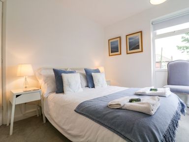 A bedroom with a bed side tables lamps pillows and a chair at The Bridge House Southwold