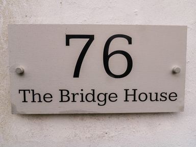 A house number sign with the number 76 and The Bridge House on a wall at The Bridge House Southwold