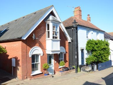 A street view of two adjacent houses one with red bricks and one with light blue walls at The Red Brick House in Aldeburgh