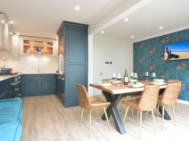 A kitchen and dining area with blue cabinets wooden dining table and brown chairs at The Red Brick House in Aldeburgh