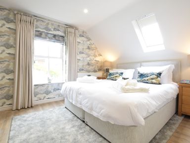 A bedroom with a bed a window with curtains and a skylight at The Red Brick House in Aldeburgh
