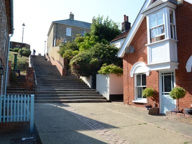 A street with stairs leading up between houses and greenery at The Red Brick House in Aldeburgh