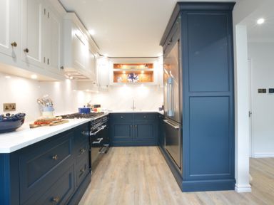 A kitchen with blue and white cabinets a stove refrigerator and wooden floor at The Red Brick House Aldeburgh