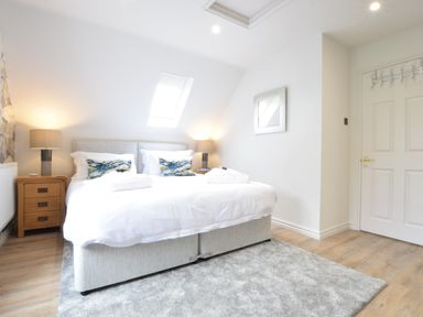 A bedroom with a double bed bedside tables lamps a skylight window and a door at The Red Brick House in Aldeburgh