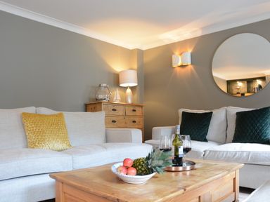 A living room with two beige sofas a wooden coffee table with fruit and wine at The Red Brick House Aldeburgh