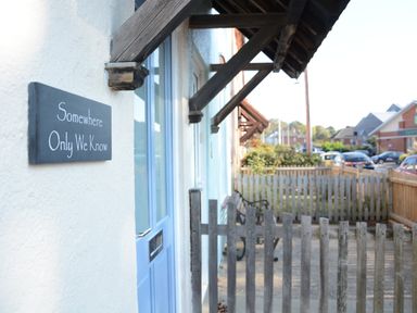 A blue door with a sign that reads Somewhere Only We Know next to a wooden fence at Somewhere Only We Know in Aldeburgh