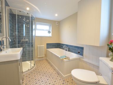 A bathroom with a corner shower, bathtub, sink, toilet, and tiled floor at Somewhere Only We Know in Aldeburgh