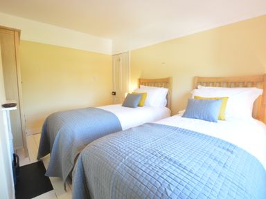 A bedroom with two single beds with blue quilts and pillows at Somewhere Only We Know in Aldeburgh
