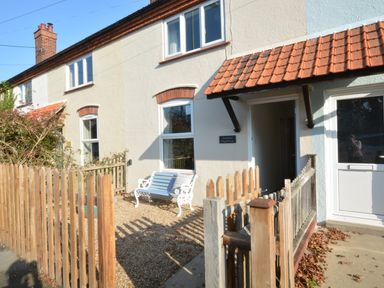 A front yard with a wooden fence and bench outside a house with a tiled roof at Somewhere Only We Know in Aldeburgh