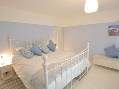 A bedroom with a white metal bed frame and blue and white pillows at Somewhere Only We Know in Aldeburgh