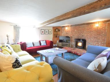 A living room with sofas and a coffee table in front of a brick wall and a wood stove at The White House with Studio in Wortwell