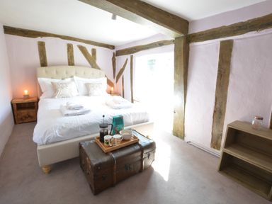 A bedroom with a bed a wooden trunk as a table and exposed wooden beams at The White House with Studio in Wortwell