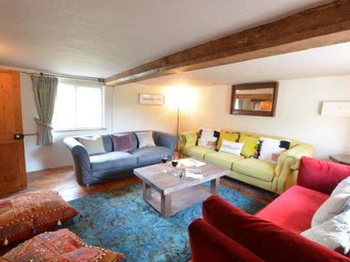 A living room with three sofas a wooden coffee table and a window at The White House with Studio in Wortwell