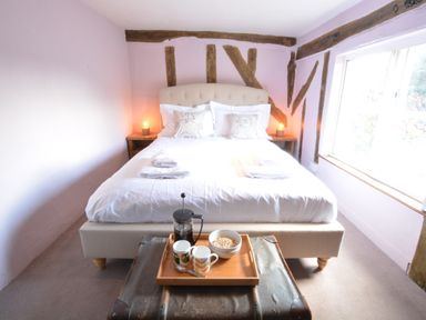 A bedroom with a bed, side tables with lamps, a window, and a tray with mugs, a bowl, and a coffee press at The White House with Studio in Wortwell