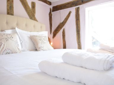 A bedroom with a bed headboard pillows and folded towels on the bed at The White House with Studio in Wortwell