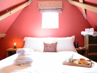 A bedroom with a bed with white linens and a wooden tray with croissants and cups at The White House with Studio in Wortwell