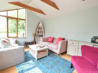 A living room with sofas a coffee table a bookshelf and large window at The White House with Studio in Wortwell