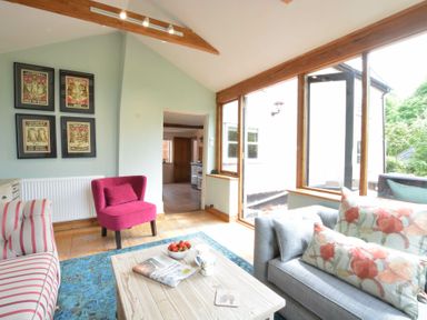 A sitting room with a wooden coffee table and large windows at The White House with Studio in Wortwell