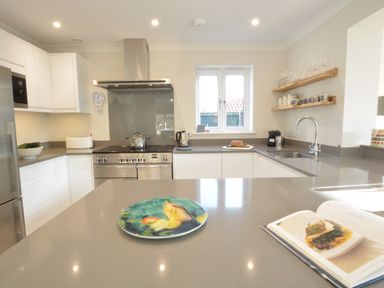 A kitchen with a stove a sink open cookbook and decorative plate on the counter at Mellows Thorpeness in Thorpeness