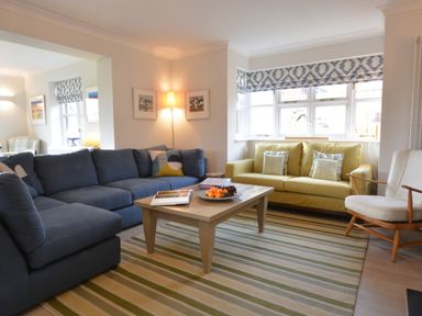 A living room with blue and yellow sofas a wooden coffee table and a striped rug at Mellows Thorpeness in Thorpeness