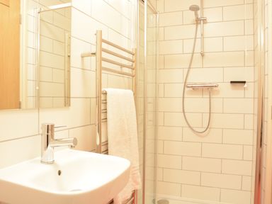 A bathroom with a sink faucet towel rack with a towel and a shower enclosure at Mellows Thorpeness in Thorpeness