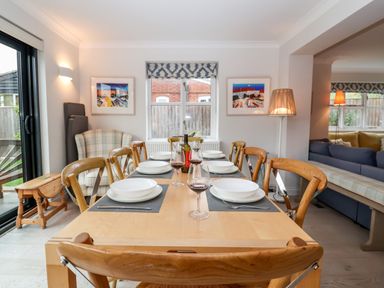 A dining room with a wooden table set with plates and wine glasses at Mellows Thorpeness in Thorpeness